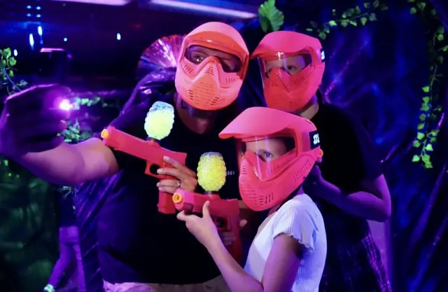 Une famille joue au gel ball sous la lumière noire